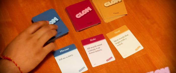 A photo of Glom, three decks of cards, with hands reaching to draw cards.