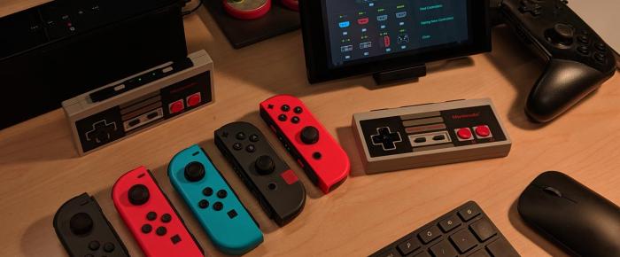 A photo of a desk with a Nintendo Switch and a group of game controllers.